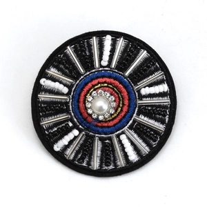 Macro shot of embroidered evil eye brooch with blue crystals and seed beads
