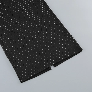 Close-up of black bodycon dress hem featuring silver rhinestones and a small side slit
