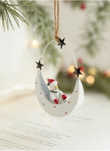 Detail of metal Christmas snowman moon ornament with red hat and stars on a rustic rope