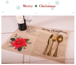 Close-up of linen Christmas placemat with red poinsettia flower and Merry Christmas text