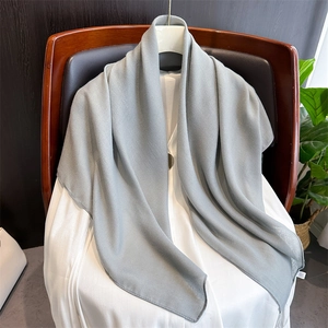 Detailed close-up of soft gray solid linen cotton scarf draped on a wooden chair