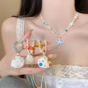 Detail of beach jewelry set featuring starfish and shell charms on woven cord