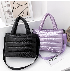 Detail of glossy quilted down fabric on black and purple puffer tote bags with straps