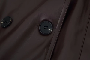 Details einer dunkelbraunen Lederjacke mit Marmorknöpfen und vertikalen Ziernähten
