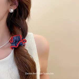 Retro denim hair scrunchie with red edges shown on a low ponytail hair tie