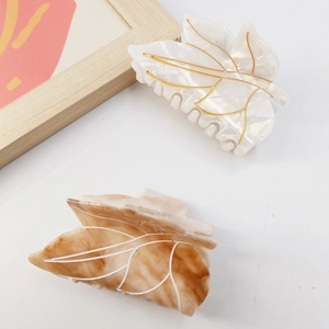 Detail of leaf-shaped acetate hair claws in white mother-of-pearl and amber marble pattern