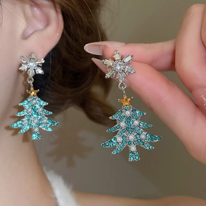Detail of Christmas tree earrings with green crystals and pearls worn by a model