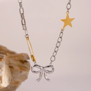 Detalle de collar con lazo plateado, imperdible dorado y charms de estrellas en roca