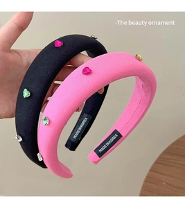 Close-up of pink and black sponge headbands with colorful heart rhinestones and Korea label