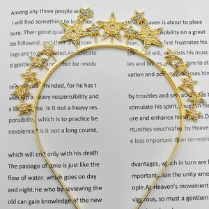 Detail of gold star headband with embedded pearls and sparkling rhinestones on text background