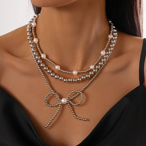 Three-layer silver bead and faux pearl necklace set with a metallic bow pendant