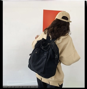 Rear view of a model wearing a minimalist black washed canvas backpack for daily use