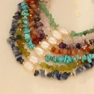 Macro shot of natural gemstones, pearls and gold beads on a beige leather background