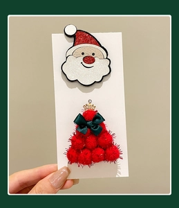 Detail of glitter Santa Claus and red plush Christmas tree hair clips on cardstock