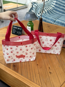 Waterproof PVC cherry bear printed tote bags on wooden table in outdoor cafe setting