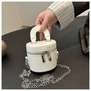 Détail d'un sac à main cylindrique blanc en cuir PU avec chaîne argentée et double zip