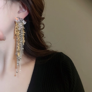 Detail of luxury rhinestone flower tassel earrings with golden leaf elements and long chains
