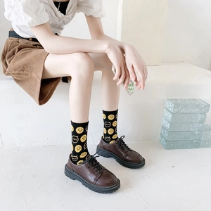Smiling face cotton mid-calf socks in black with brown platform loafers on white stairs