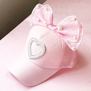 Close-up of pink mesh cap featuring a large lace bow and heart-shaped pearl detailing