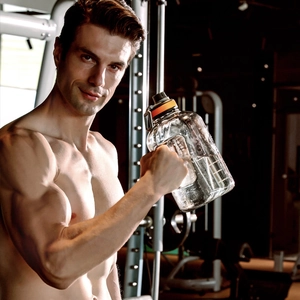 Male athlete holding 2.5L BPA free fitness water bottle in a gym setting