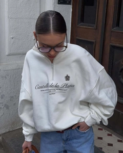 Detail of white half-zip sweatshirt featuring black cursive chest print and stand collar