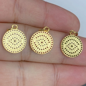 Three gold-plated evil eye pendants with cubic zirconia held on fingertips for size detail