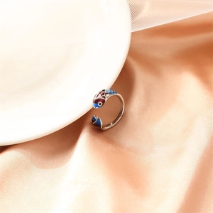 Detail of koi fish ring with colorful enamel hanging on a white porcelain bowl