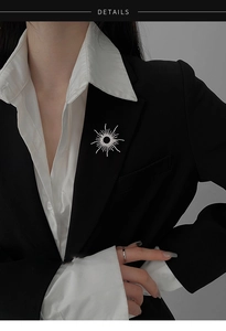 Detailed view of sunray brooch with cubic zirconia on black blazer lapel