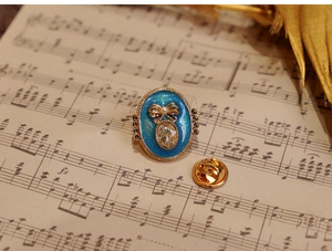 Macro detail of blue enamel flower brooch with rhinestones and pearl on vintage music sheet
