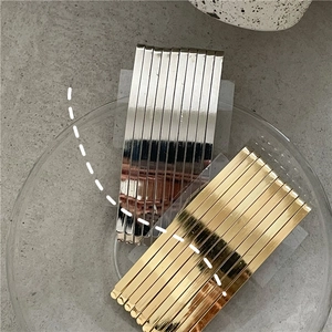Set of 10 gold and silver metal hair clips displayed on a glass tray for styling