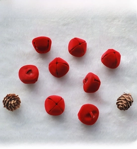 Detail shot of 2.5cm red flocked Christmas bells on white faux fur with pine cones
