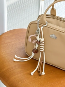 Detail van een kaki gevlochten sleutelhanger met koptelefoonhanger aan een tas