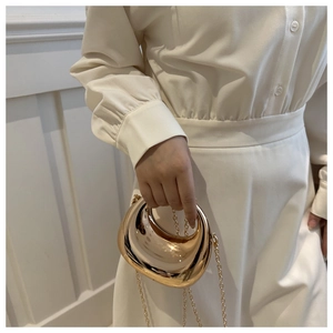 Détail d'un sac à main doré brillant en forme de croissant avec bandoulière chaîne