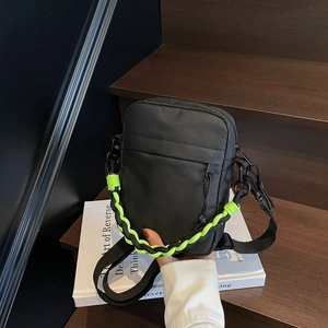 Detail of black nylon crossbody bag with bold neon yellow woven decorative chain strap