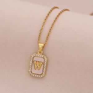 Détail d'un pendentif en or 18K avec incrustation de nacre blanche et lettre W dorée