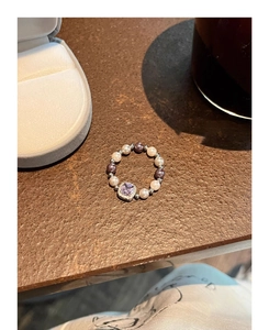 Detail view of pearl elastic ring with a square lavender zircon stone and micro-pave crystals