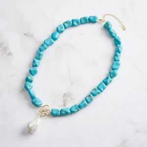 Detail of baroque pearl pendant with turquoise beads and golden clover element