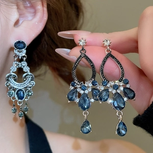 Detail of vintage silver drop earrings featuring dark blue teardrop gemstones and tassels