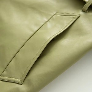 Detailed macro shot of light green leather coat pocket showing fine texture and stitching
