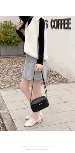 Detail of black quilted shoulder bag with chain strap shown in a chic outdoor cafe setting