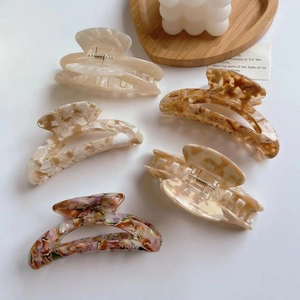 Close-up of assorted acetate hair claws on a wooden tray with a minimalist aesthetic