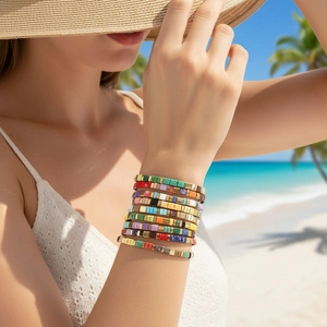 Colorful Tila bead stack bracelets with gold square accents worn at a tropical beach