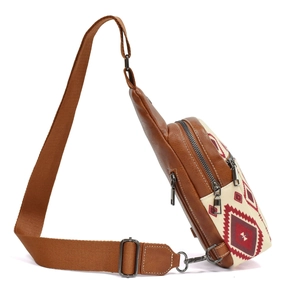 Detail of bohemian canvas sling bag with multiple zippers and brown leather trim