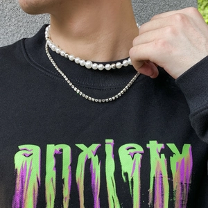 Detail of layered pearl and silver rhinestone chain necklaces on a male model