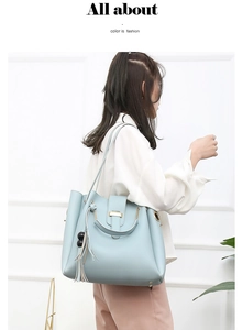 Detail view of light blue tote bag with decorative tassel and metal ring handle on model