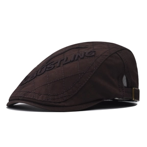 Detail of dark brown newsboy cap featuring diamond quilting and embossed lettering