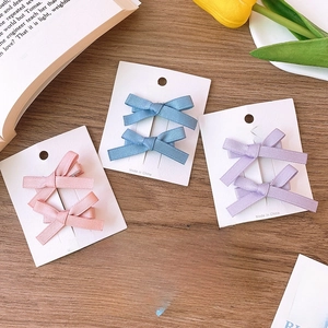 Detailed view of handmade satin ribbon bow hair clips in assorted pastel colors on a wooden surface