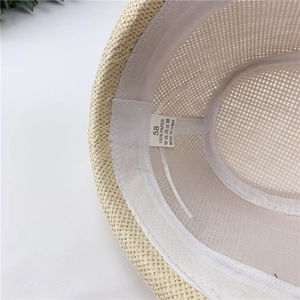 Detail view of woven straw hat interior with 100% paper material tag and 58cm size label