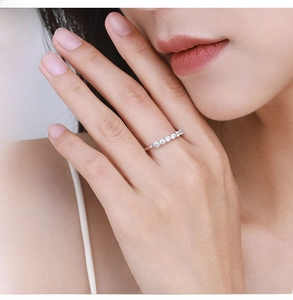 Dettaglio di un anello in argento S925 con sette diamanti pavé sul dito di una modella