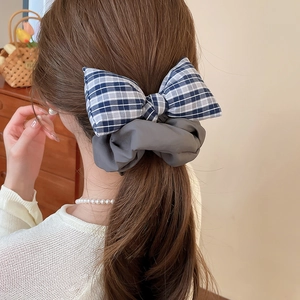 Close-up of blue and white checkered fabric bow hair scrunchie on a dark brown ponytail